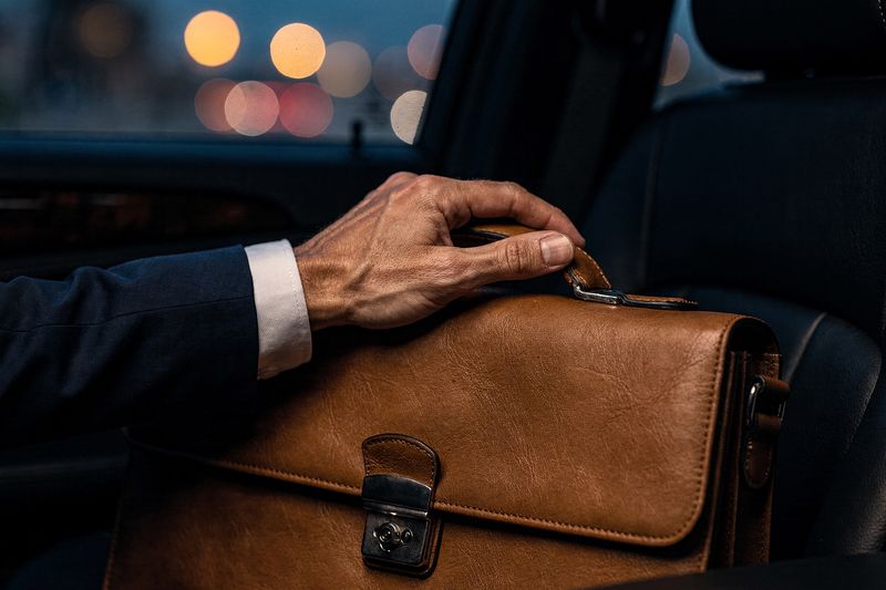 A business traveller's briefcase on the back seat of a luxury car